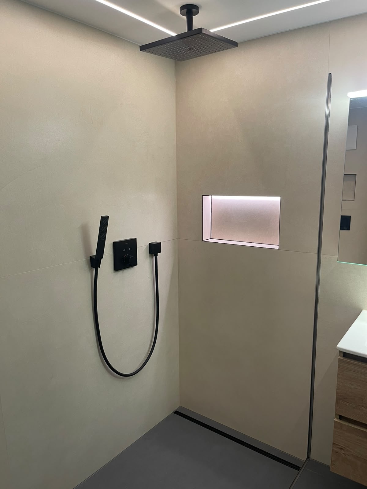 Bodengleiche Dusche mit schwarzen Armaturen und beleuchteter Nische