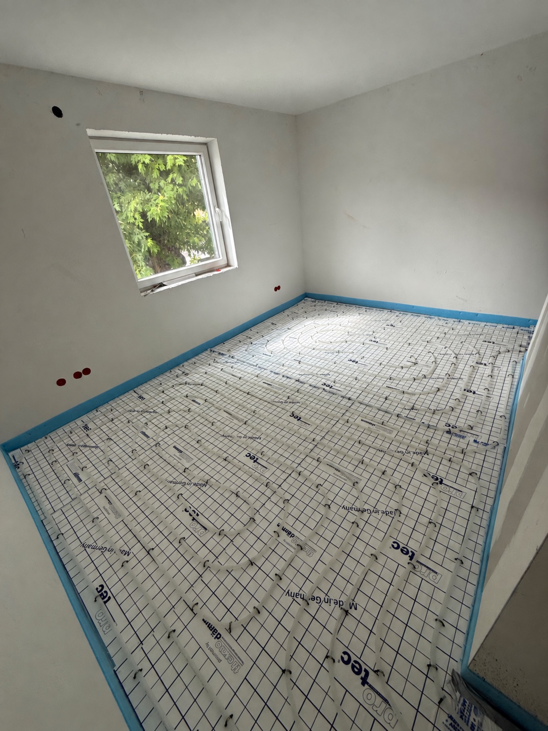 Verlegte Rohre einer Fußbodenheizung in einem Raum vor dem Estricheinbau