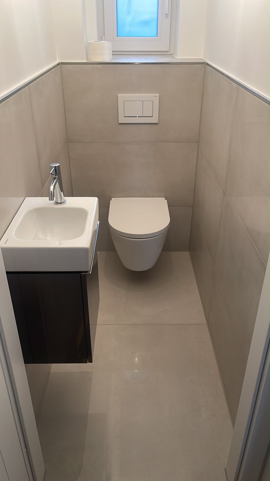 Helles Gäste-WC mit kompaktem Waschtisch, dunklem Unterschrank und wandhängendem WC