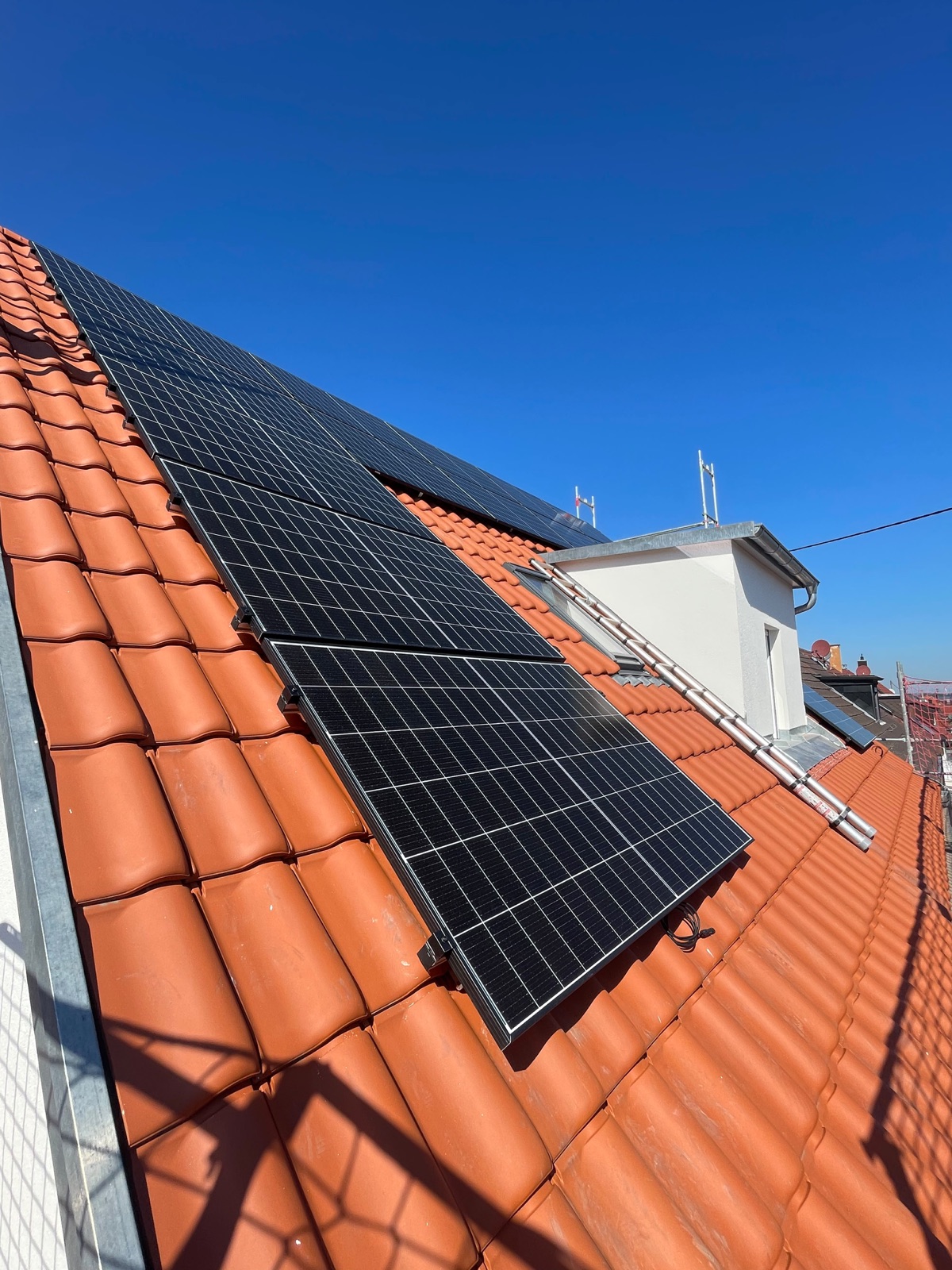 Photovoltaikmodule auf einem roten Ziegeldach bei blauem Himmel